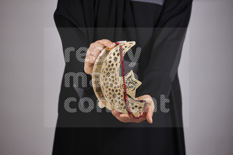 A woman in black abaya holding different ramadan lanterns in different positions