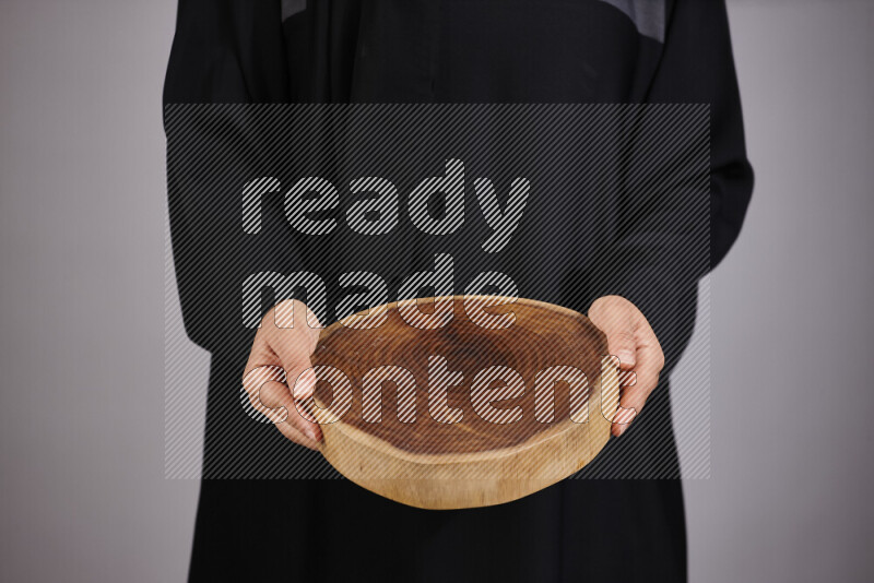 A woman in black abaya holding different wooden essentials in different positions