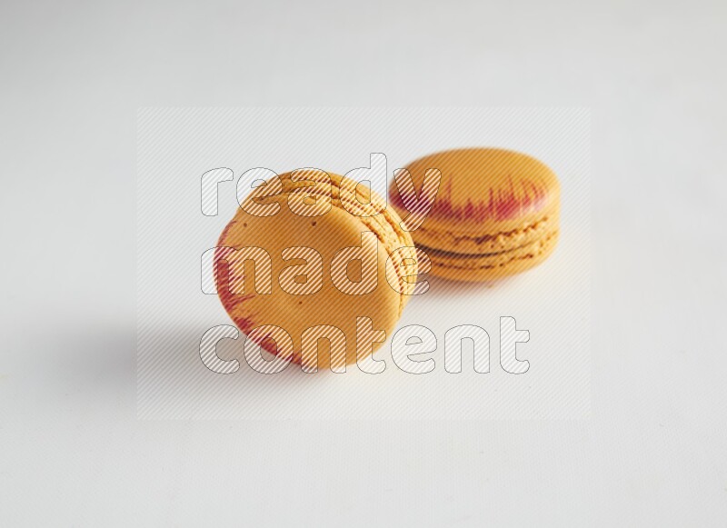 45º Shot of two orange Exotic macarons on white background