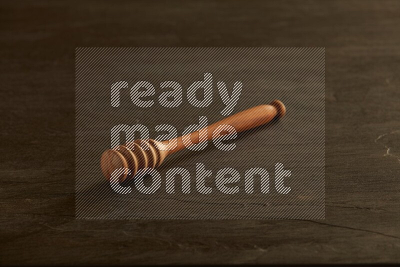 Wooden honey dipper on black slate background
