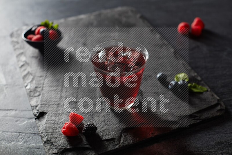 A glass of mixed berries juice on black background
