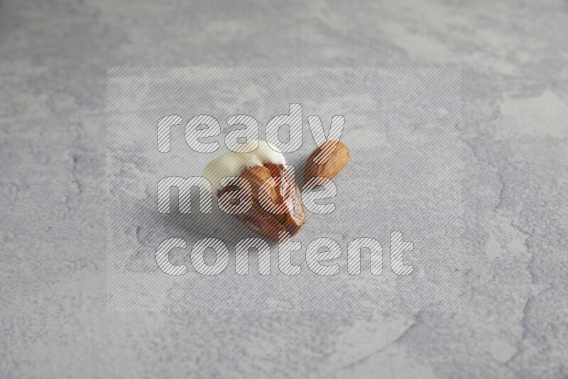 Almond stuffed date coved with white chocolate on a light grey background