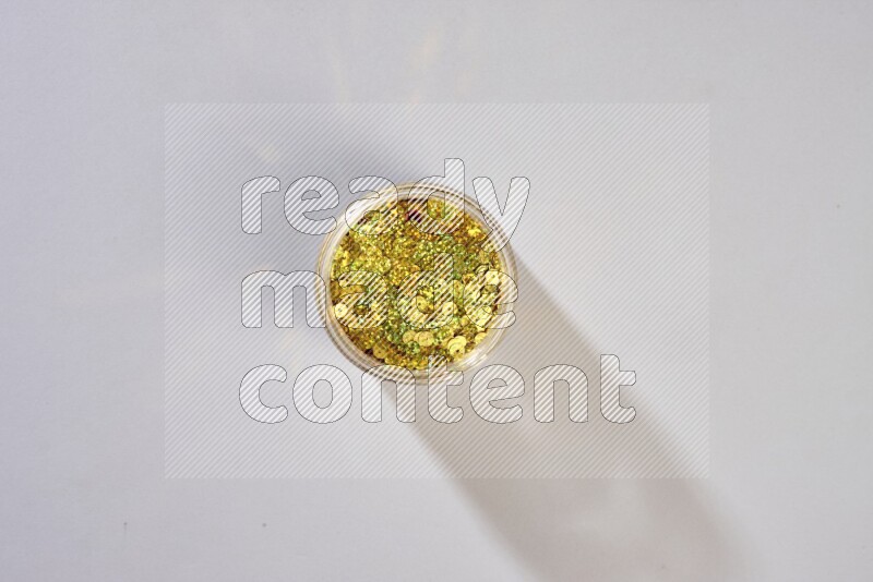 Colored flat sequins in a glass jar on grey background