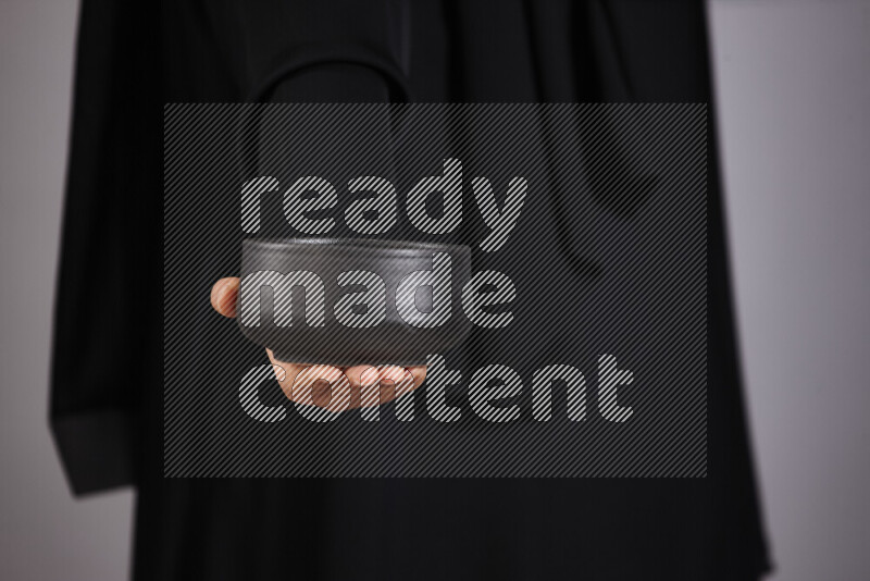 امرأة ترتدي عباءة سوداء تحمل أدوات فخارية مختلفة في أوضاع متعددة