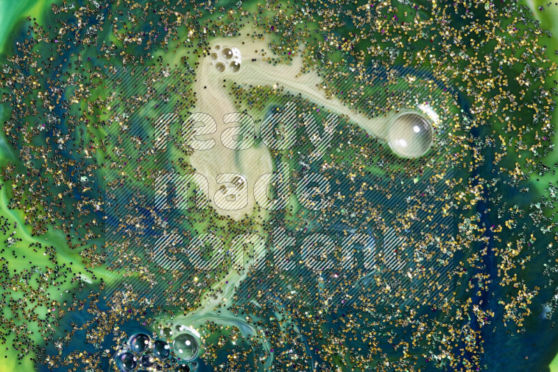 A close-up of sparkling gold glitter scattered on swirling blue and green background
