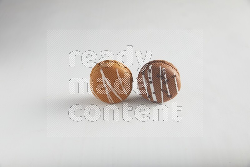 45º Shot of of two assorted Brown Irish Cream, and Brown white Chocolate Caramel macarons on white background
