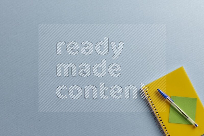 A yellow notebook with different school supplies on blue background