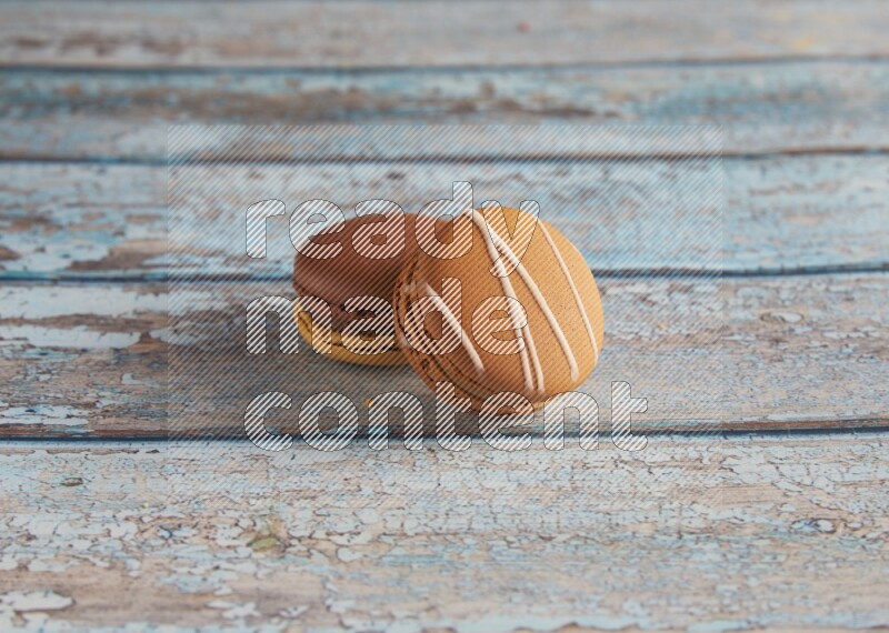 45º Shot of of two assorted Brown Irish Cream, and Yellow, and Brown Chai Latte macarons  on light blue background