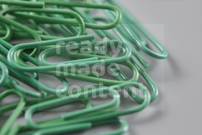 Green paper clips isolated on a grey background