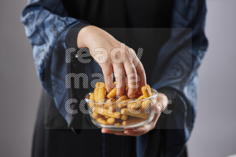 Woman in abaya holding different kinds of snacks in different positions