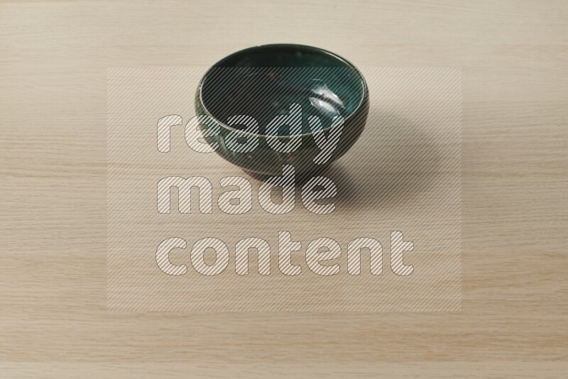 A dark green pottery bowl on light wooden background