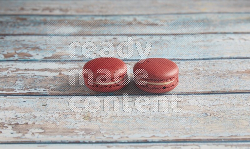45º Shot of two Red Velvet macarons on light blue wooden background