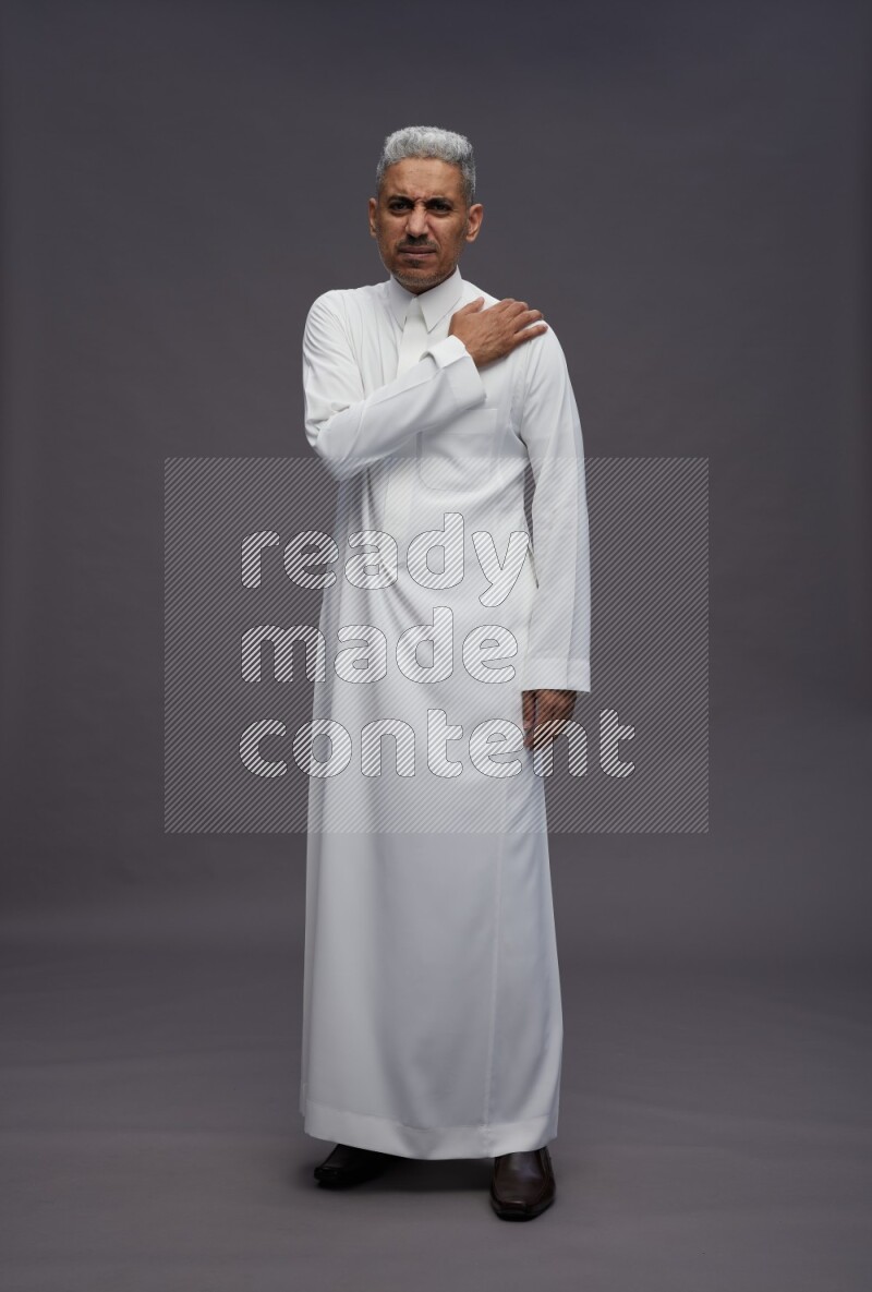 Saudi man wearing thob standing interacting with the camera on gray background