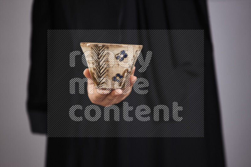 A woman in black abaya holding different pottery essentials in different positions