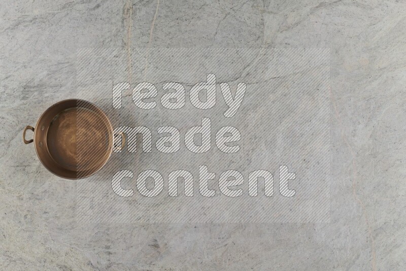 A small copper pan on grey marble background