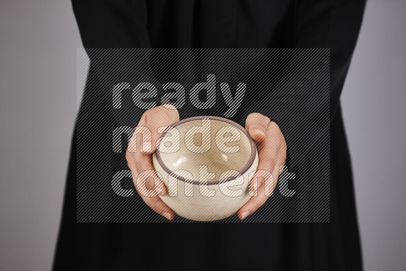 A woman in black abaya holding different pottery essentials in different positions