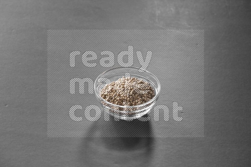 A glass bowl full of white peppers on black flooring