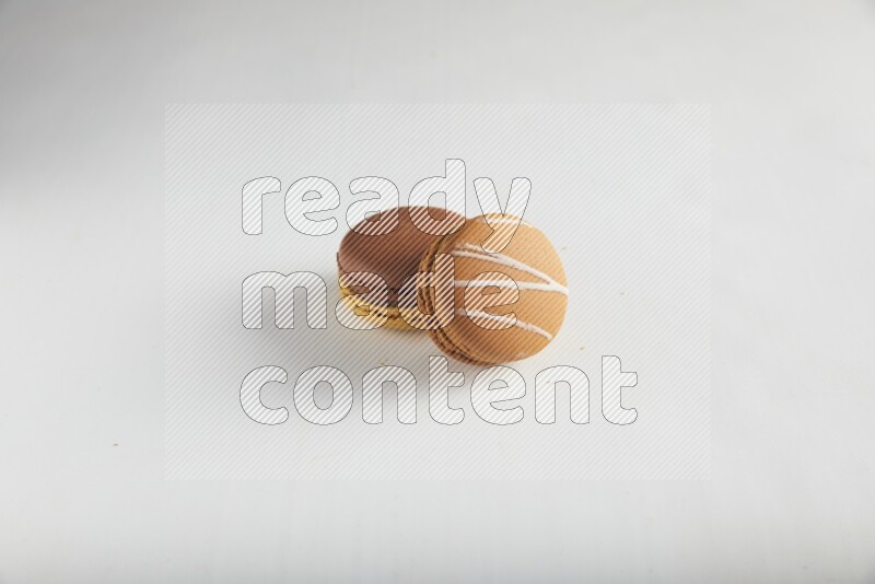 45º Shot of of two assorted Brown Irish Cream, and Yellow, and Brown Chai Latte macarons on white background