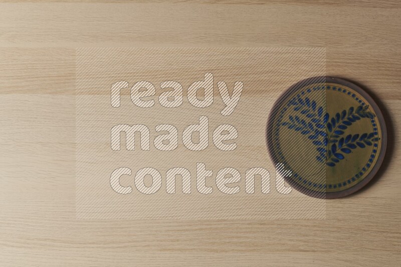 A decorative pottery plate on light wooden background