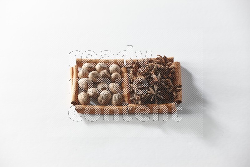 مربعان من أعواد القرفة ممتلئان باليانسون النجمي وجوزة الطيب علي خلفية بيضاء