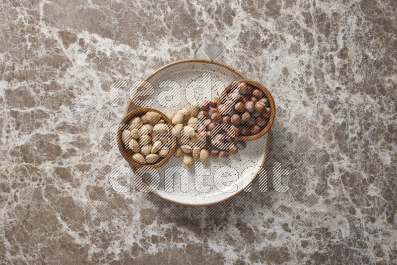 Nuts in pottery plates and wooden bowls in a light setup