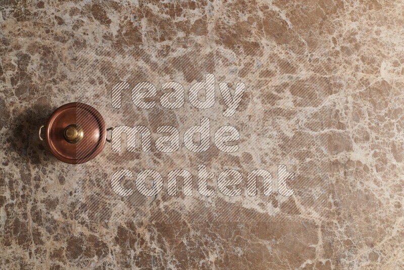 A small copper pot on beige marble background
