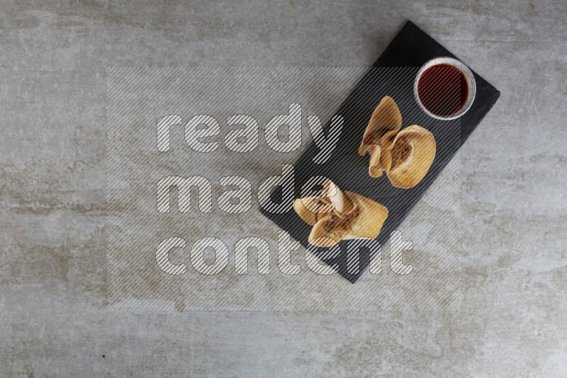 wonton cups with soy sauce ramkin on rectangle slate on grey textured counter top