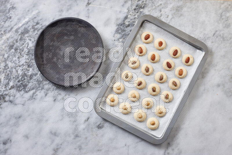 Ghoriba step by step with its ingredient, flour, powdered sugar, ghee and nuts on grey marble background