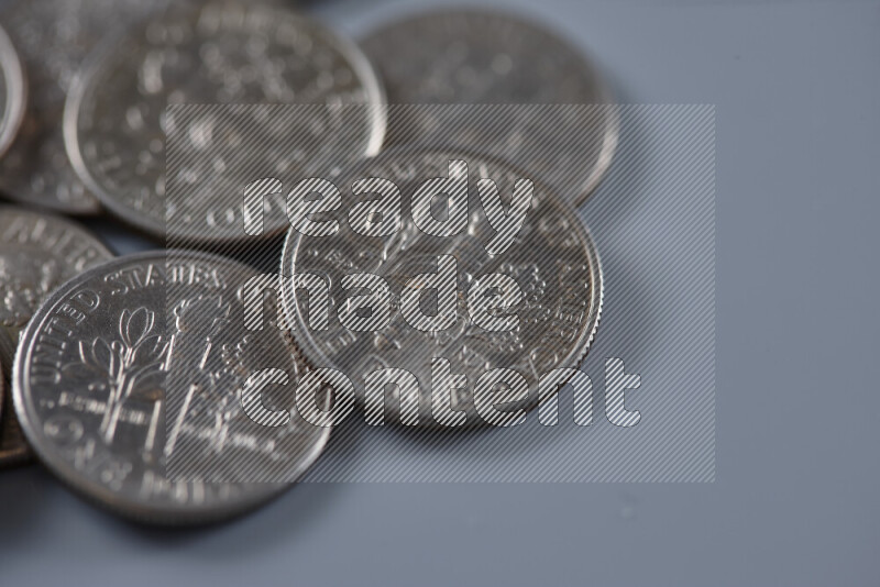 A close-up of scattered United States one dime coins on grey background