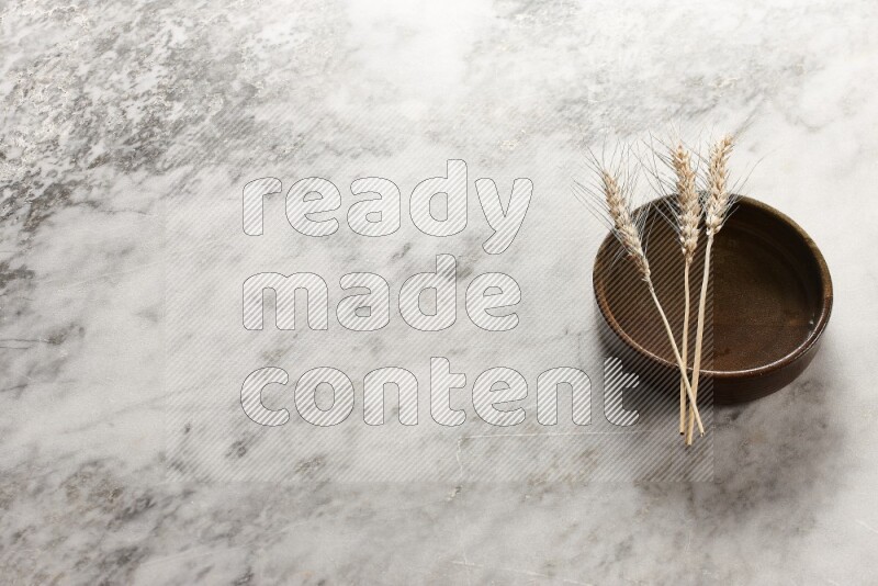 Wheat stalks on multicolored pottery oven plate on grey marble background