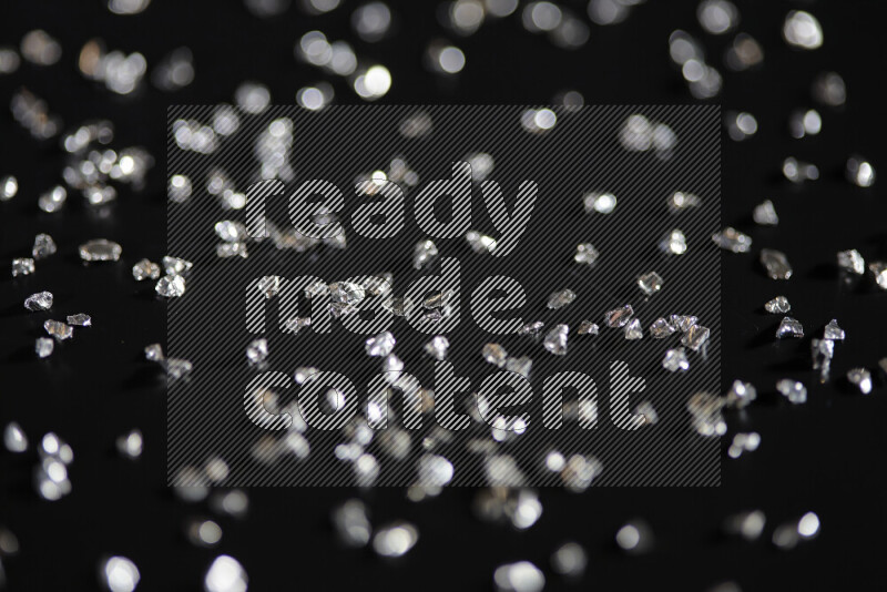 Silver shimmering fragments of glass scattered on a black background