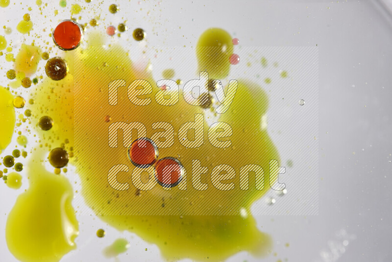 Close-ups of abstract red, green and yellow watercolor drops on oil Surface on white background