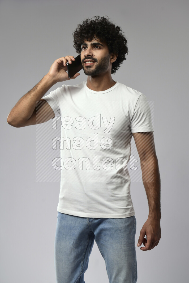 A man wearing casual standing and talking on the phone on white background