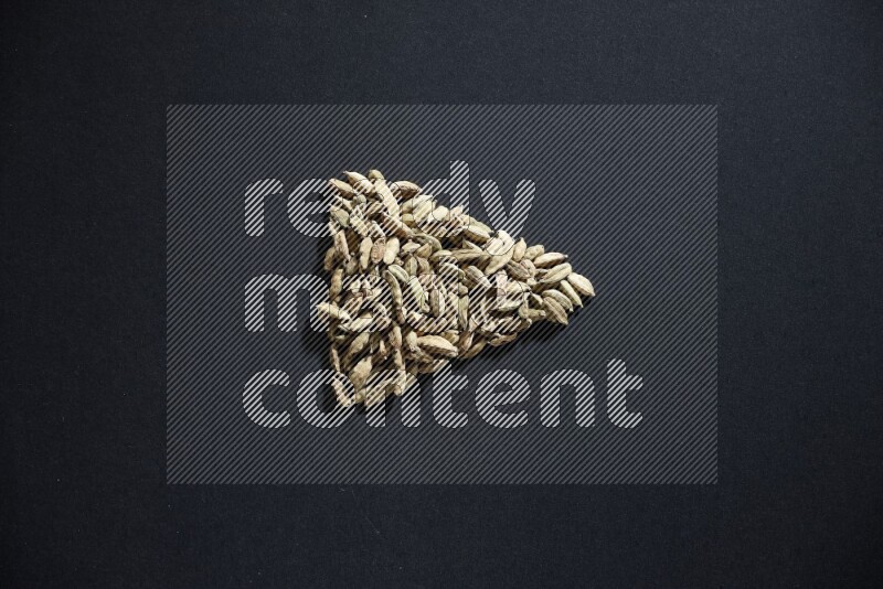 Cardamom in a triangle shape on black flooring