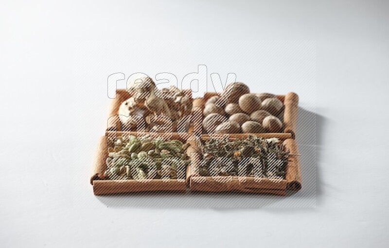 4 squares of cinnamon sticks full of nutmegs, dried ginger, cardamom and dried basil on white flooring