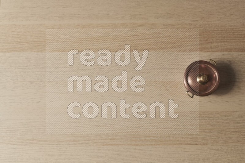 A small copper pot on light wooden background