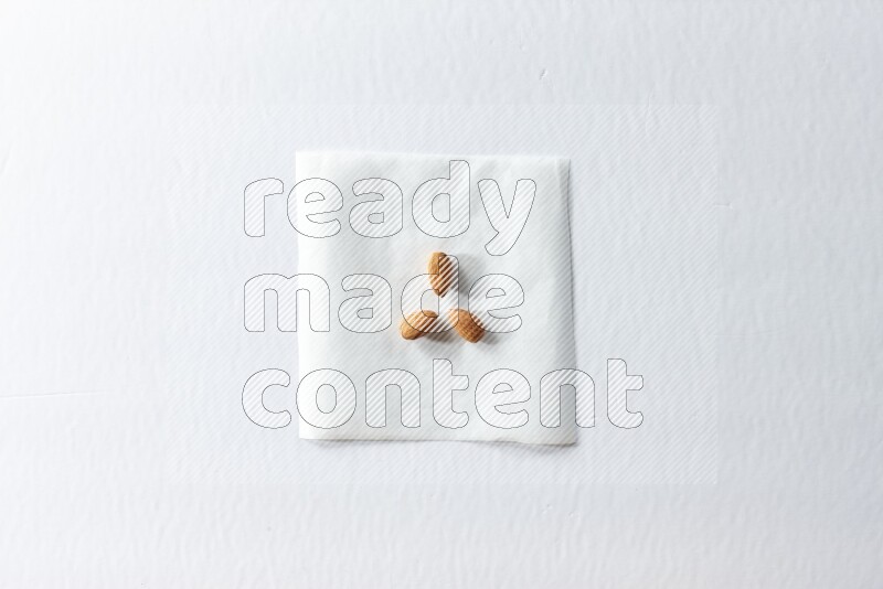 3 peeled almonds on a piece of paper on a white background in different angles