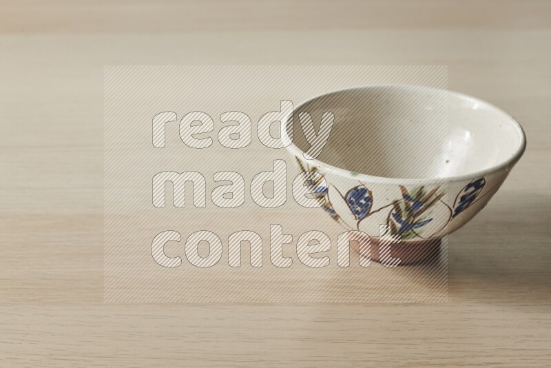A decorative pottery bowl on light wooden background