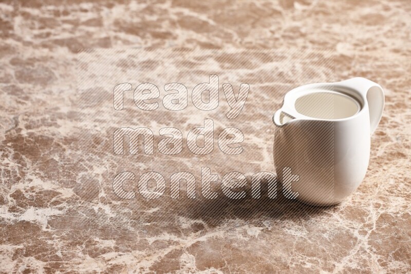 A ceramic milk jug on beige marble background