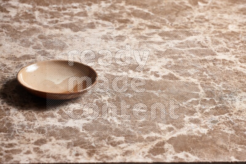 A beige pottery plate on beige marble background