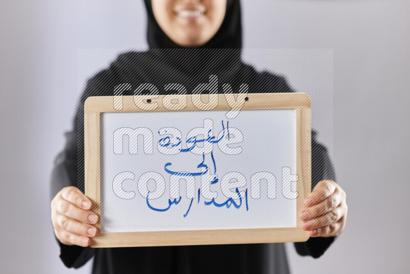 A woman in abaya holding books and a board in different positions (back to school)