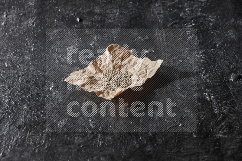 حبوب الفلفل الأبيض في قطعة من الورق على أرضية سوداء