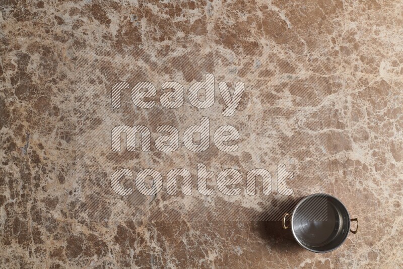 A small copper pot on beige marble background