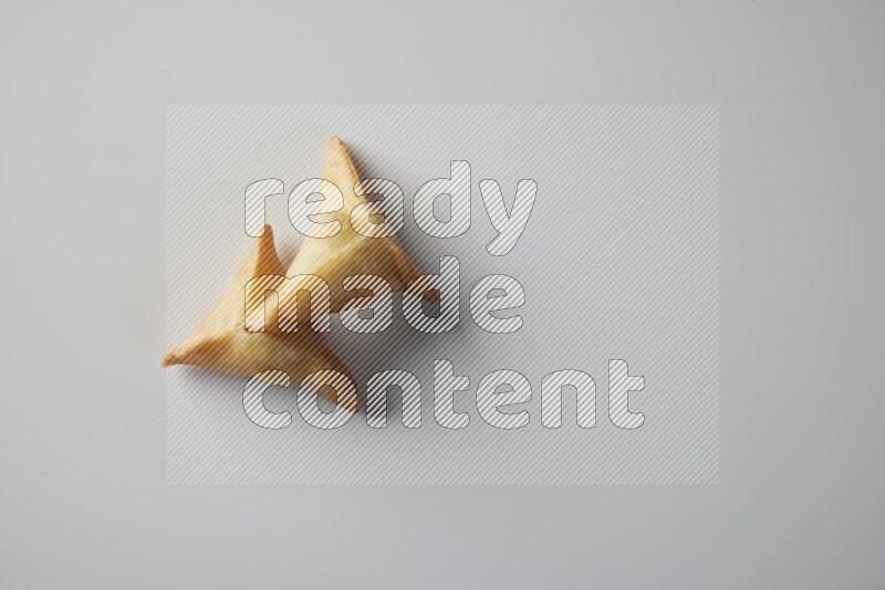 Two fried sambosa from a top angle on a white background