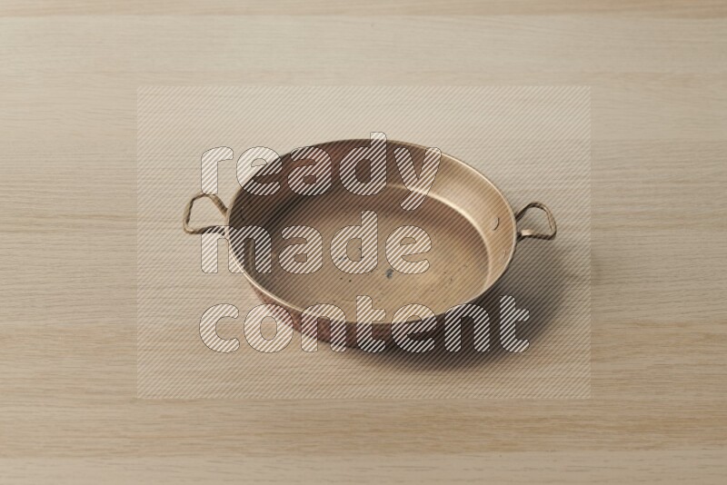 A small copper pan on light wooden background
