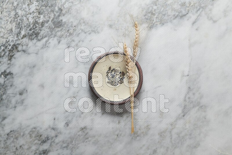 Wheat stalks on decorative pottery plate on grey marble background
