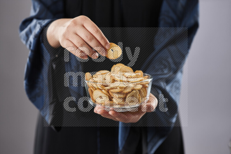 Woman in abaya holding different kinds of snacks in different positions
