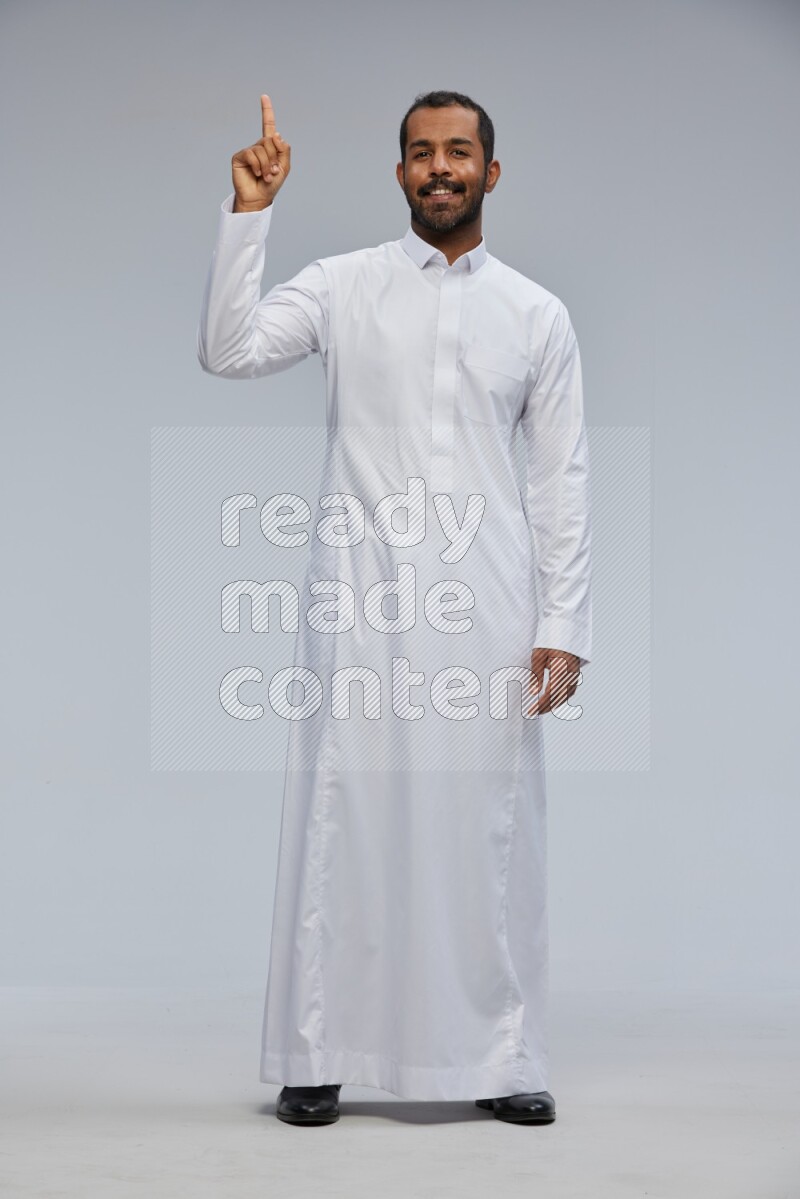 Saudi man Wearing Thob standing interacting with the camera on Gray background