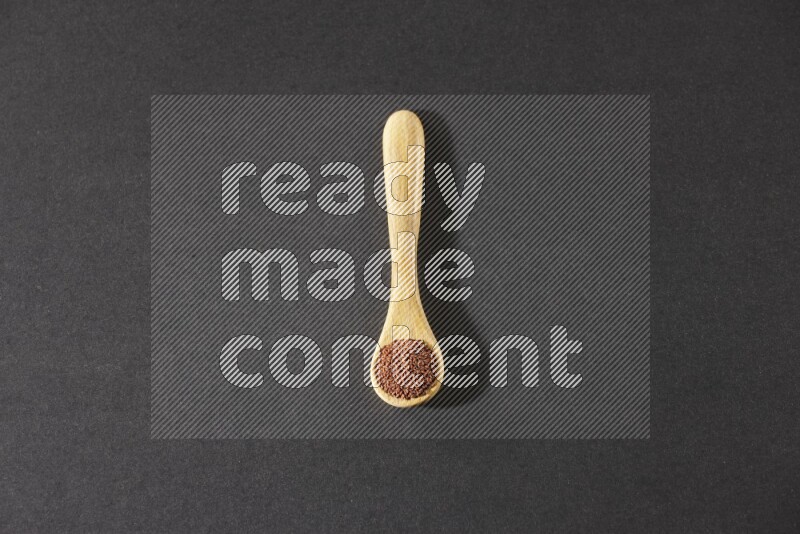 ملعقة خشبية ممتلئة ببذور حب الرشاد علي خلفية سوداء