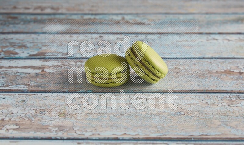 45º Shot of two Green Pistachio macarons on light blue wooden background